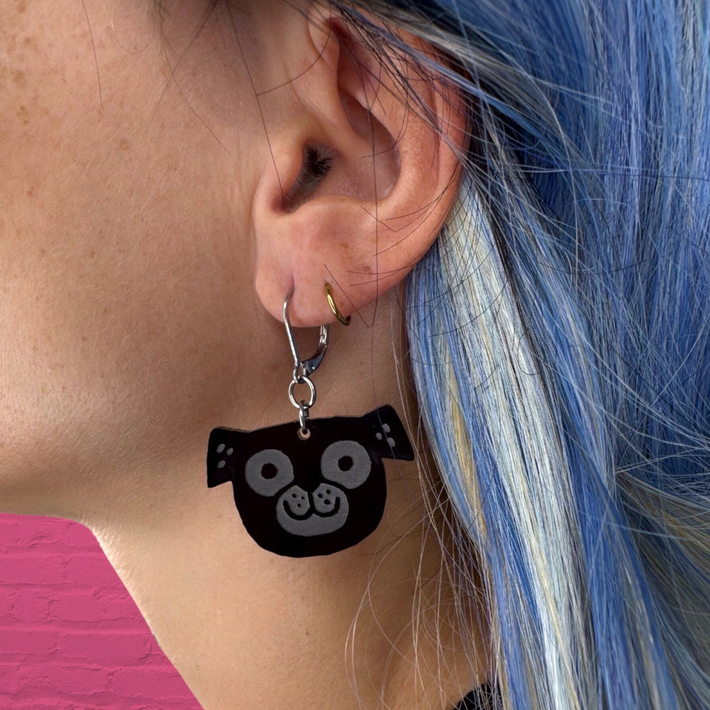 Gemma Correll's black pug earring worn by a person with bright blue hair.