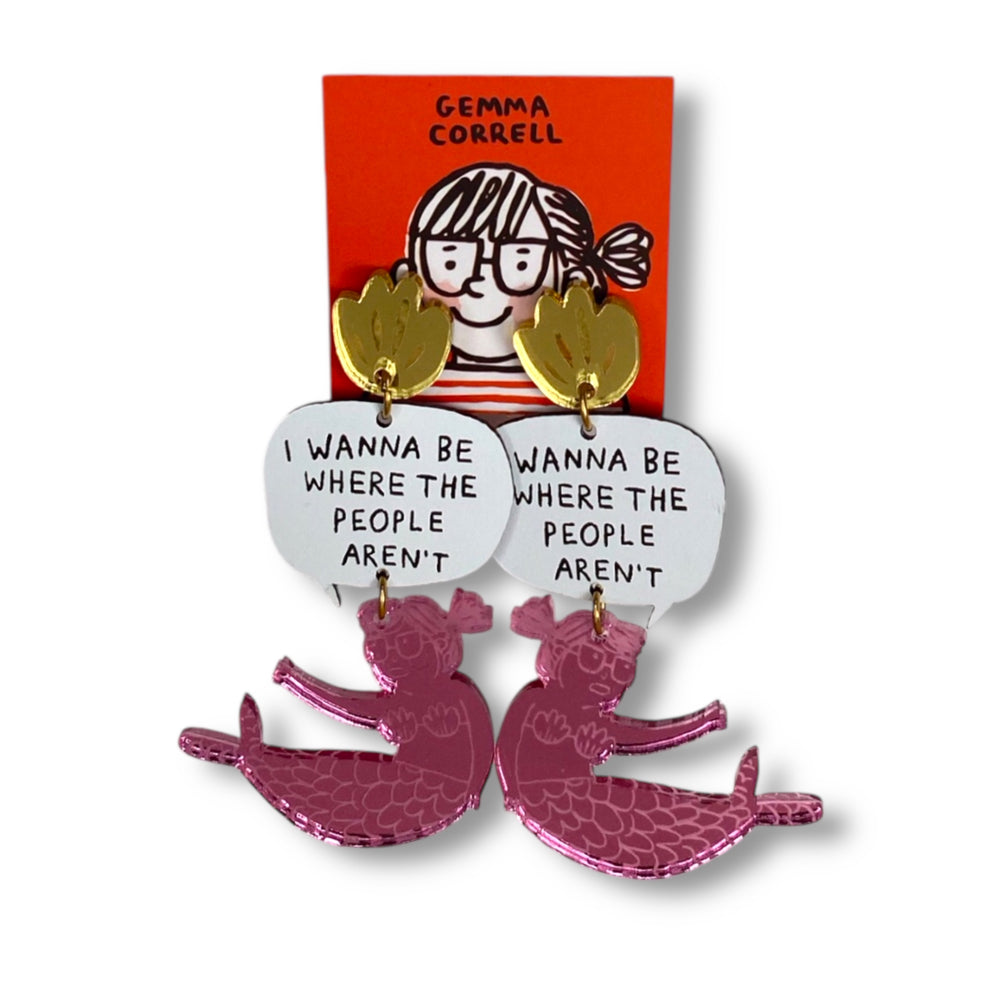 Earrings with mermaid design and speech bubble with the text 'I Wanna Be Where the People Aren't' on a Gemma Correll branded red card.