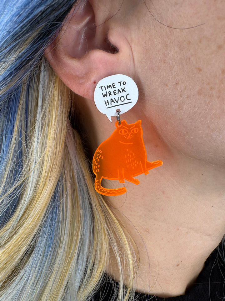 Transparent orange cat earring with a white tag worn by a person with blue and blonde hair.