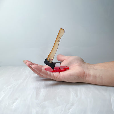 Ring holder in the shape of an axe sits in the palm of a hand. 