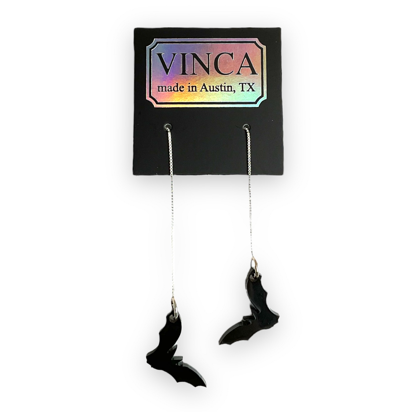 Shiny, bat charms attached to sterling silver ear threaders and threaded through a Vinca-branded hangtag.
