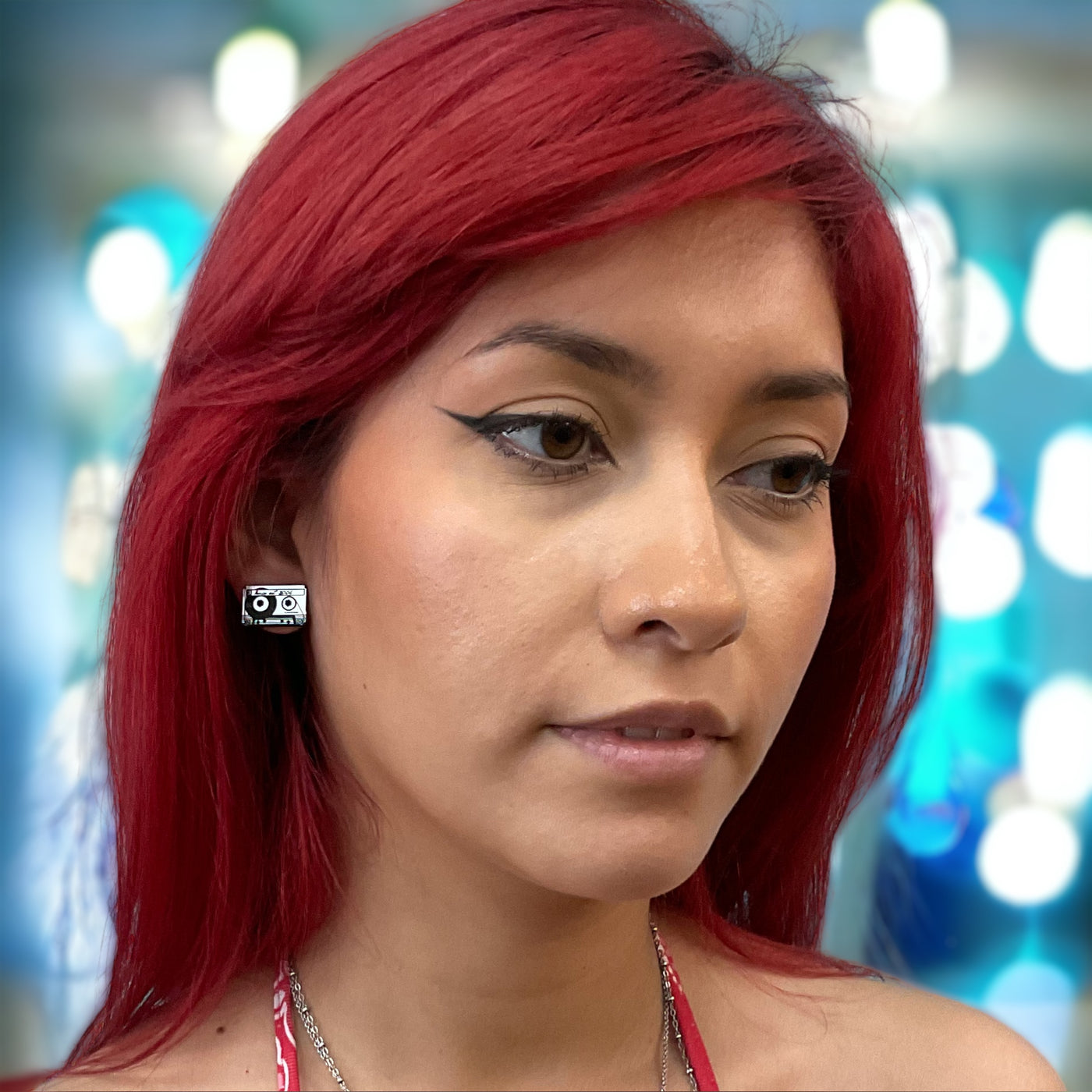 Silver tone, plastic cassette earrings on an alternatively styled model with bright red hair.