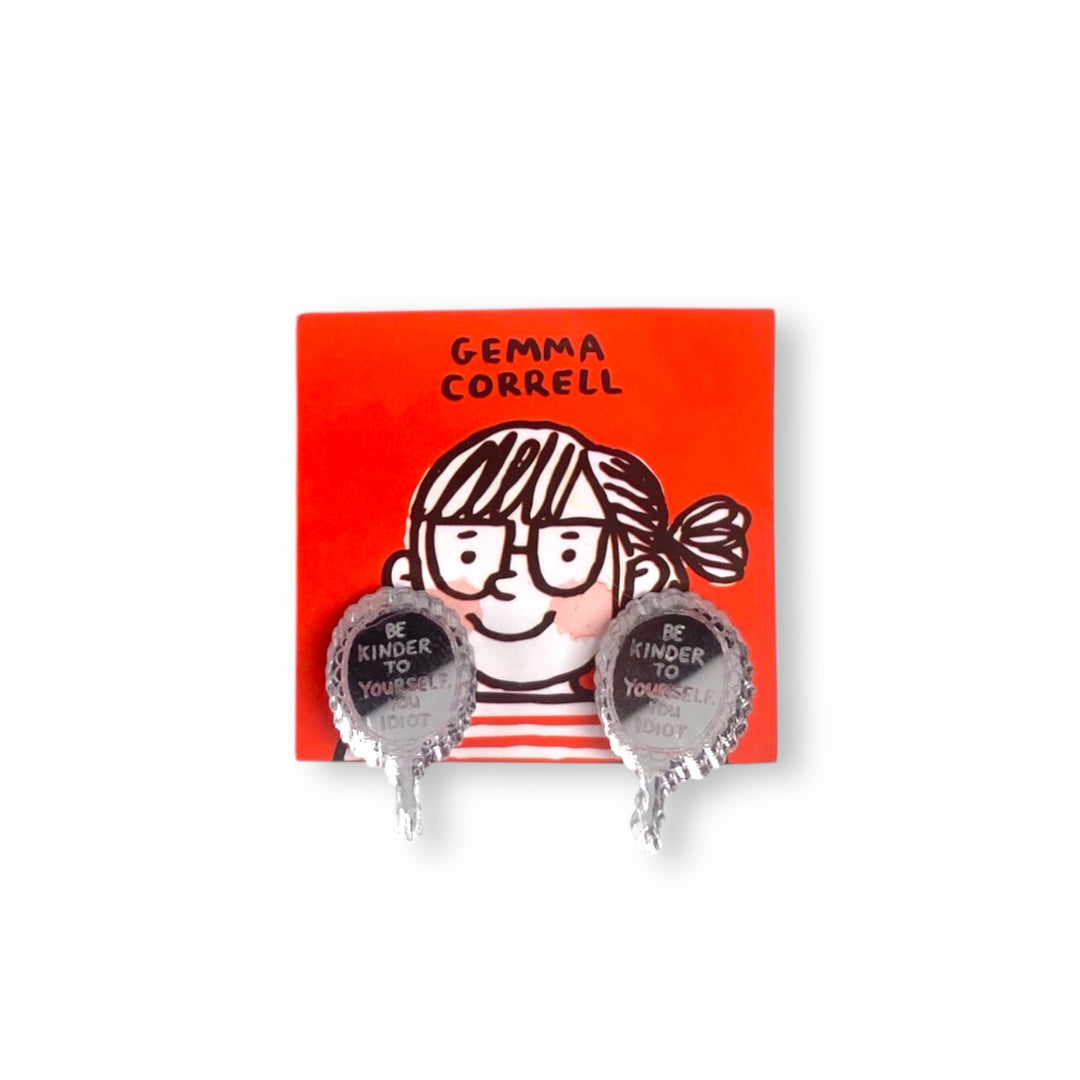 A pair of hand mirror stud earrings with the phrase, 'Be kinder to yourself, you idiot' on a red card with 'Gemma Correll' branding.