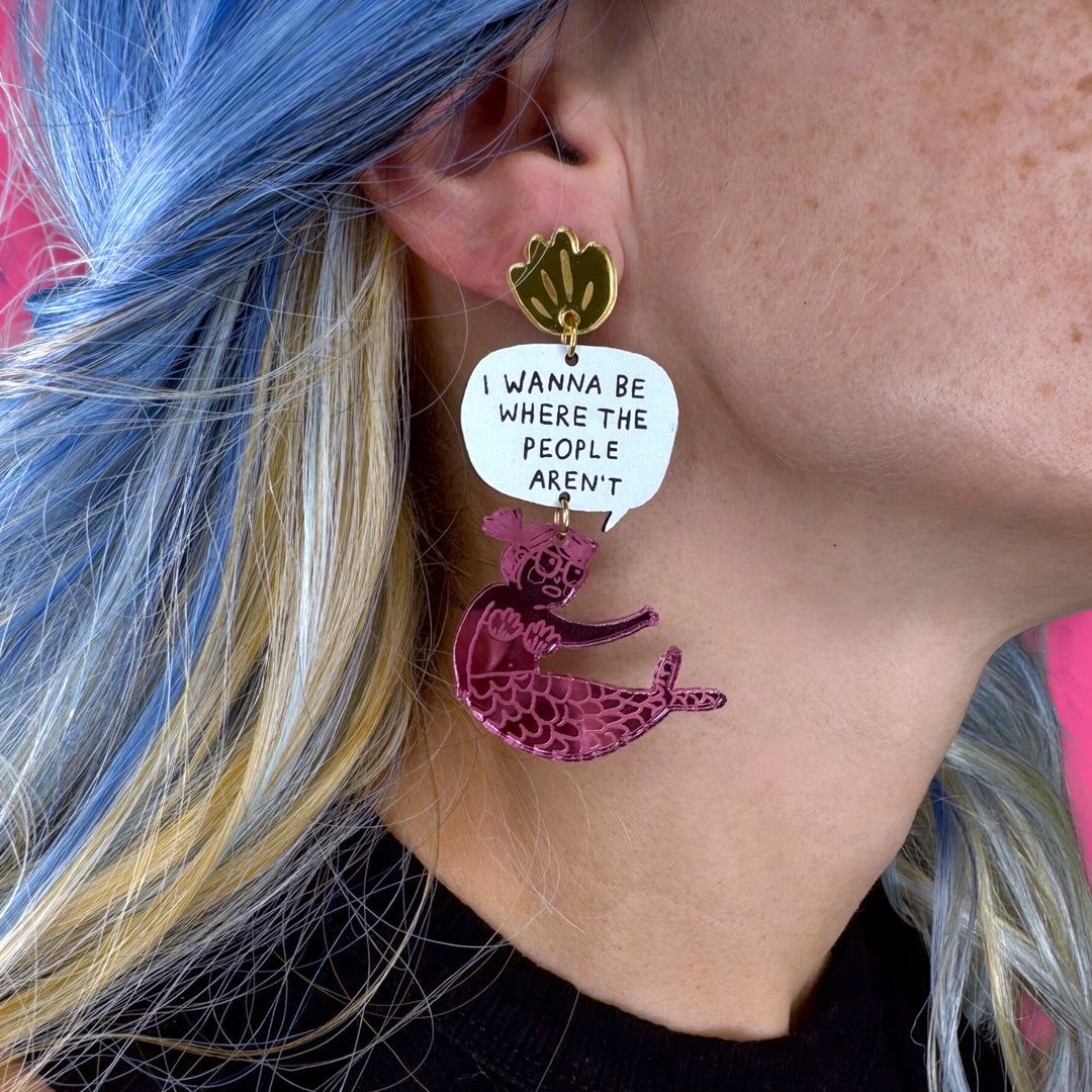 Gemma Correll illustrated mermaid design with text 'I Wanna be where the people aren't' in a speech bubble worn by a person with blue hair.