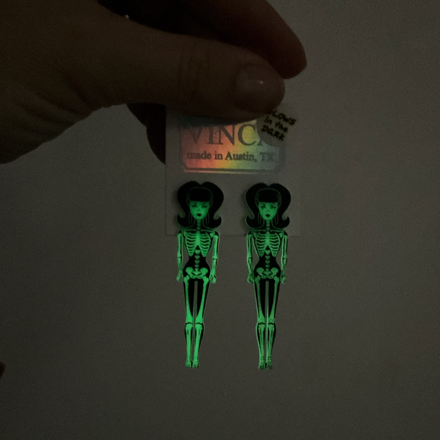 Illuminated glow-in-the-dark skeleton '60s doll earrings on a white card with the Vinca logo.