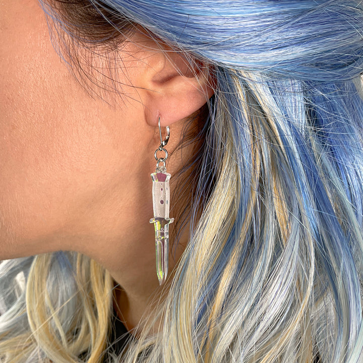 A side profile of a woman's ear wearing the Iridescent switchblade dangle earring.