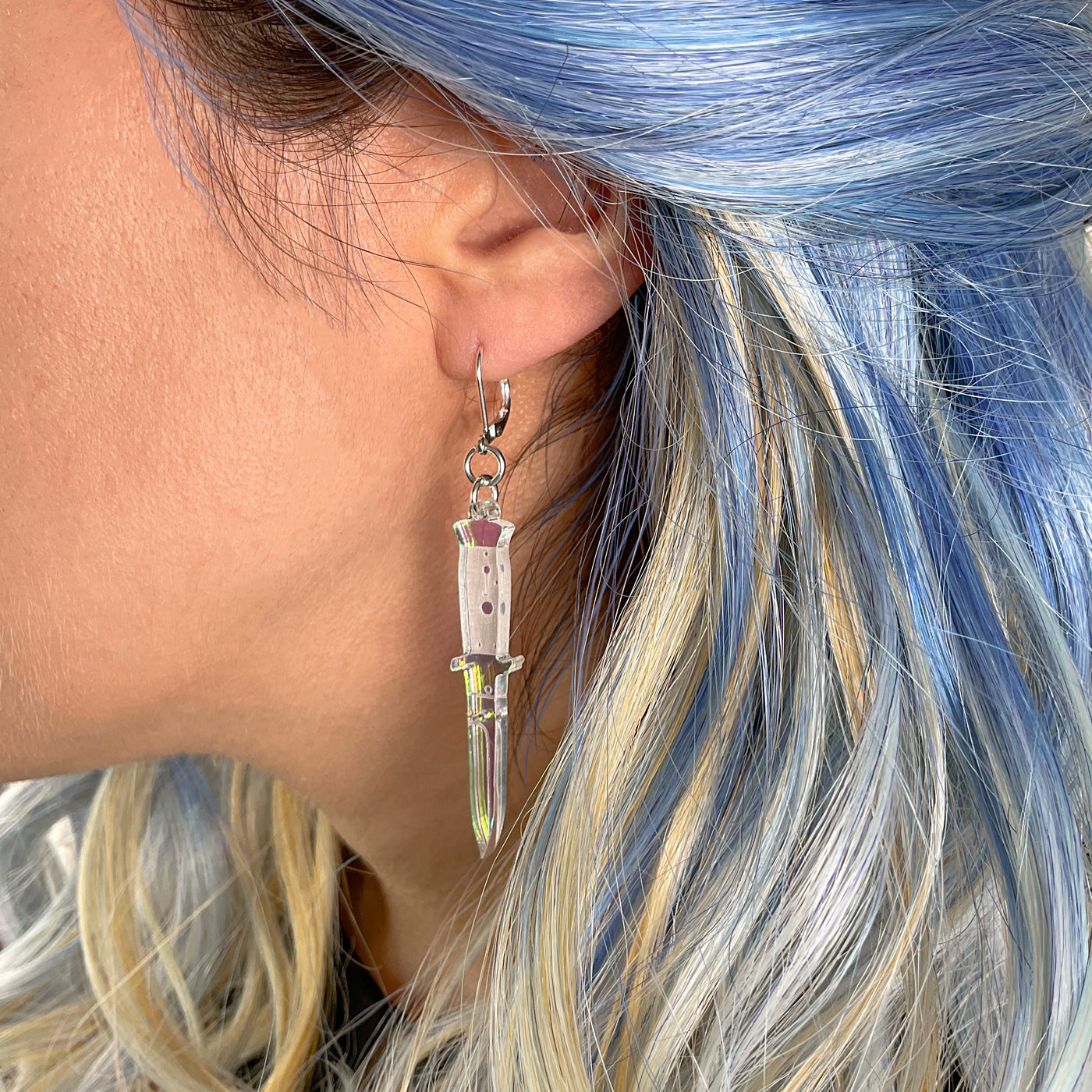 A side profile of a woman's ear wearing the Iridescent switchblade dangle earring.