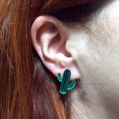 Mirror green plastic cactus earrings on a model with straight auburn hair. 