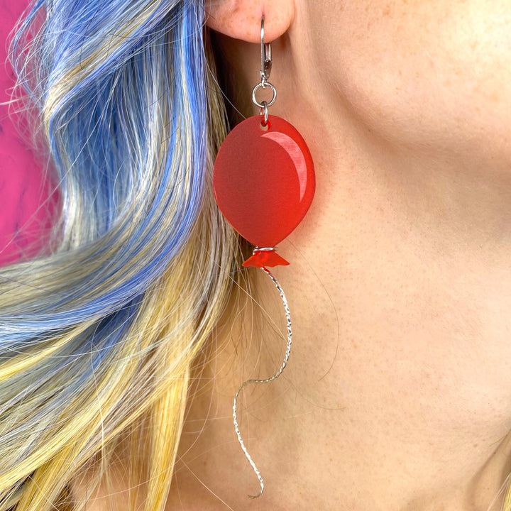 Our Frosted Red Balloon Dangle Earrings are worn by a model for scale.