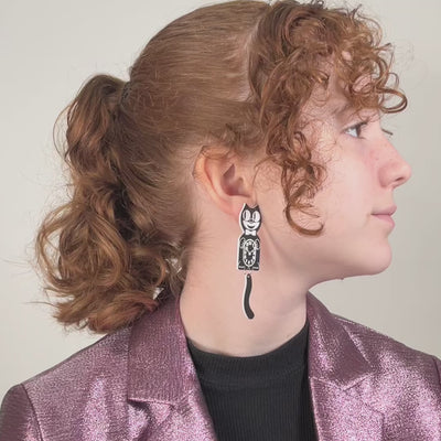 A young model turns her head to reveal an extra large Kit-Cat Klock earring and small Kit-Cat Klock earring on her left and right ear.