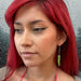 Transparent neon green lightning bolt ear threader earrings on an alternatively styled model with bright red hair.