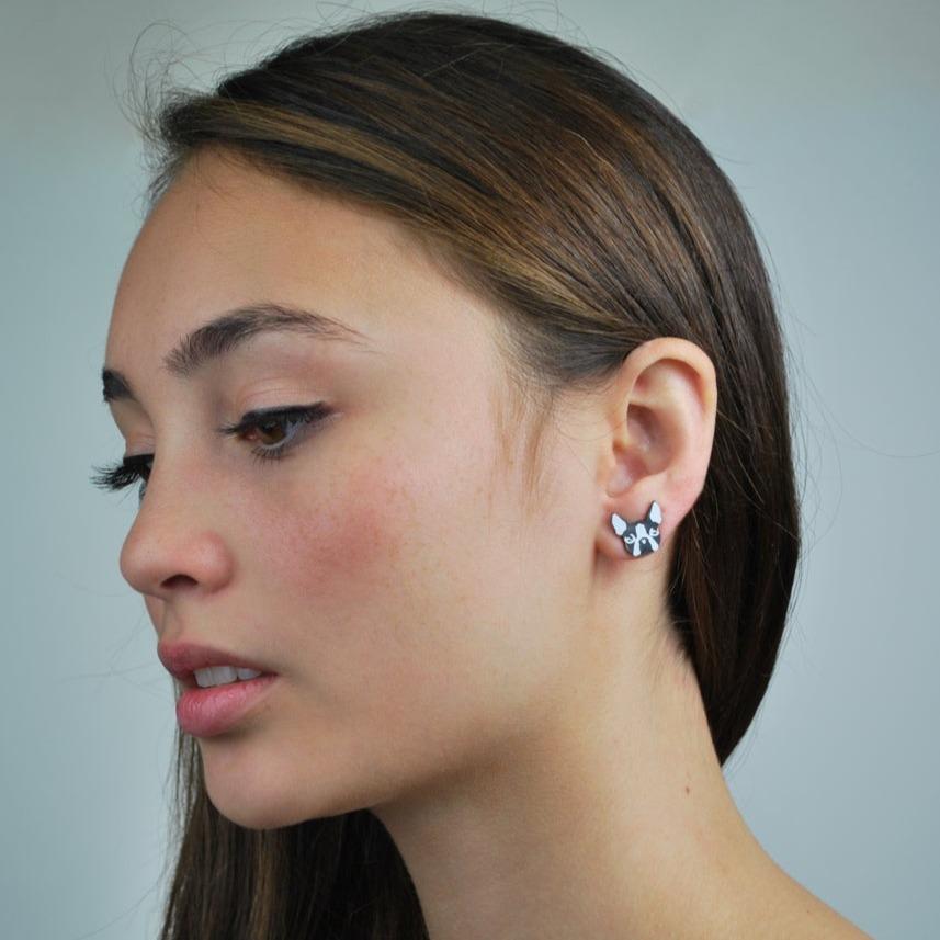 Boston Terrier stud earring on a model standing against a light blue background.