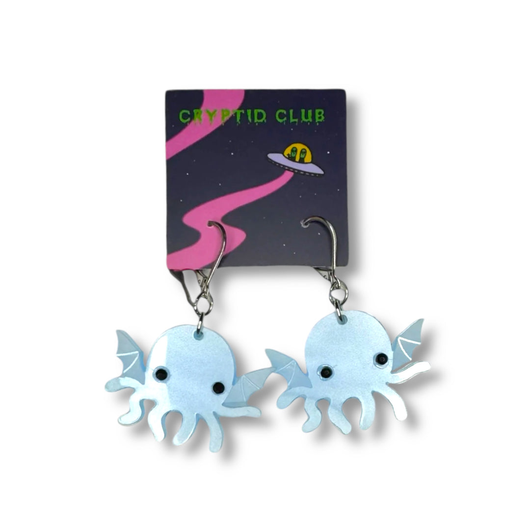 Pair of Sarah's Scribbles Cryptid Club Cthulhu earrings on a branded card set on a white background.