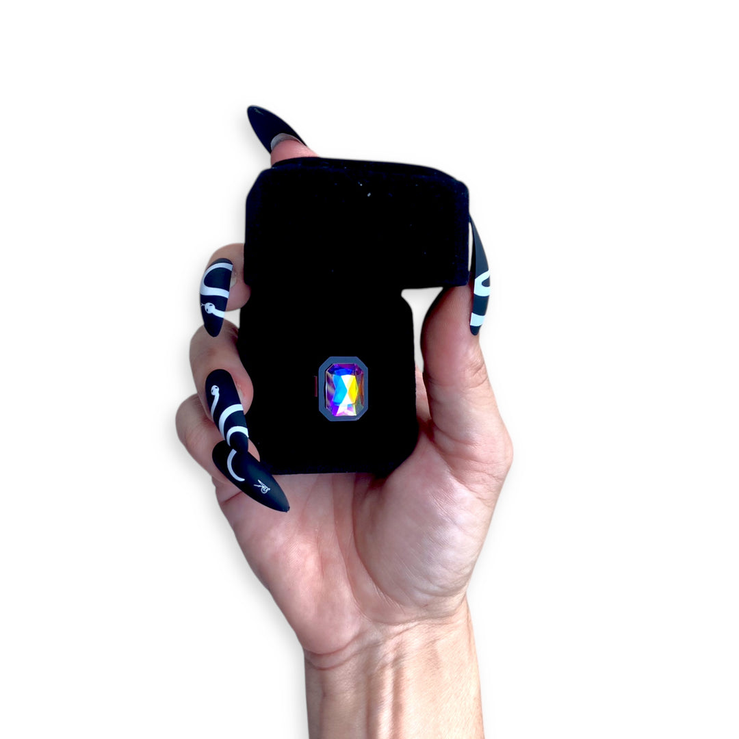 Black velvet Sorceress's adjustable ring case with a black Sorceress's  ring held by a hand.