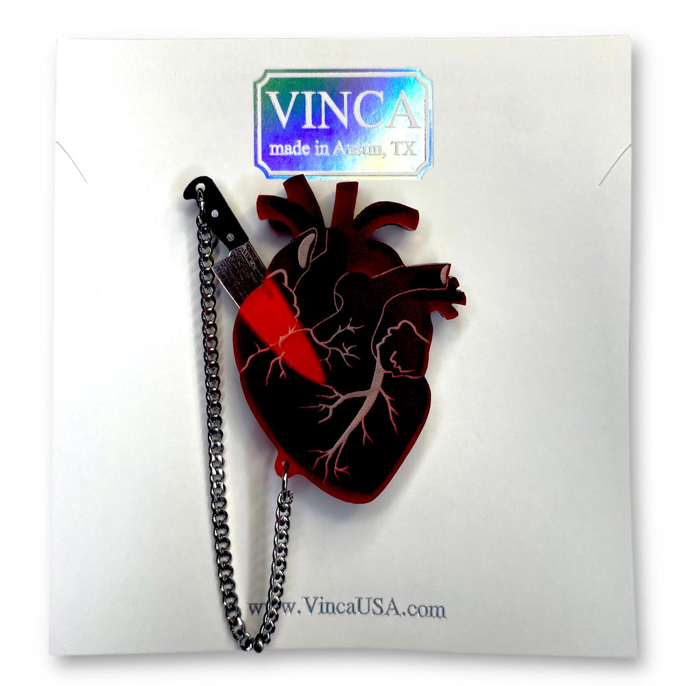 Our Heart of Aghast brooch with removable knife is on a white branded Vinca card set against a white background. 