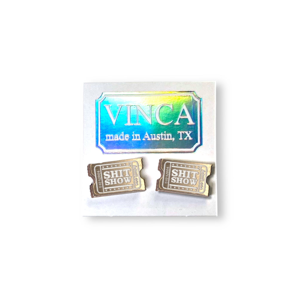Pair of gold 'SHIT SHOW' earrings with a 'VINCA' branded card on a white background