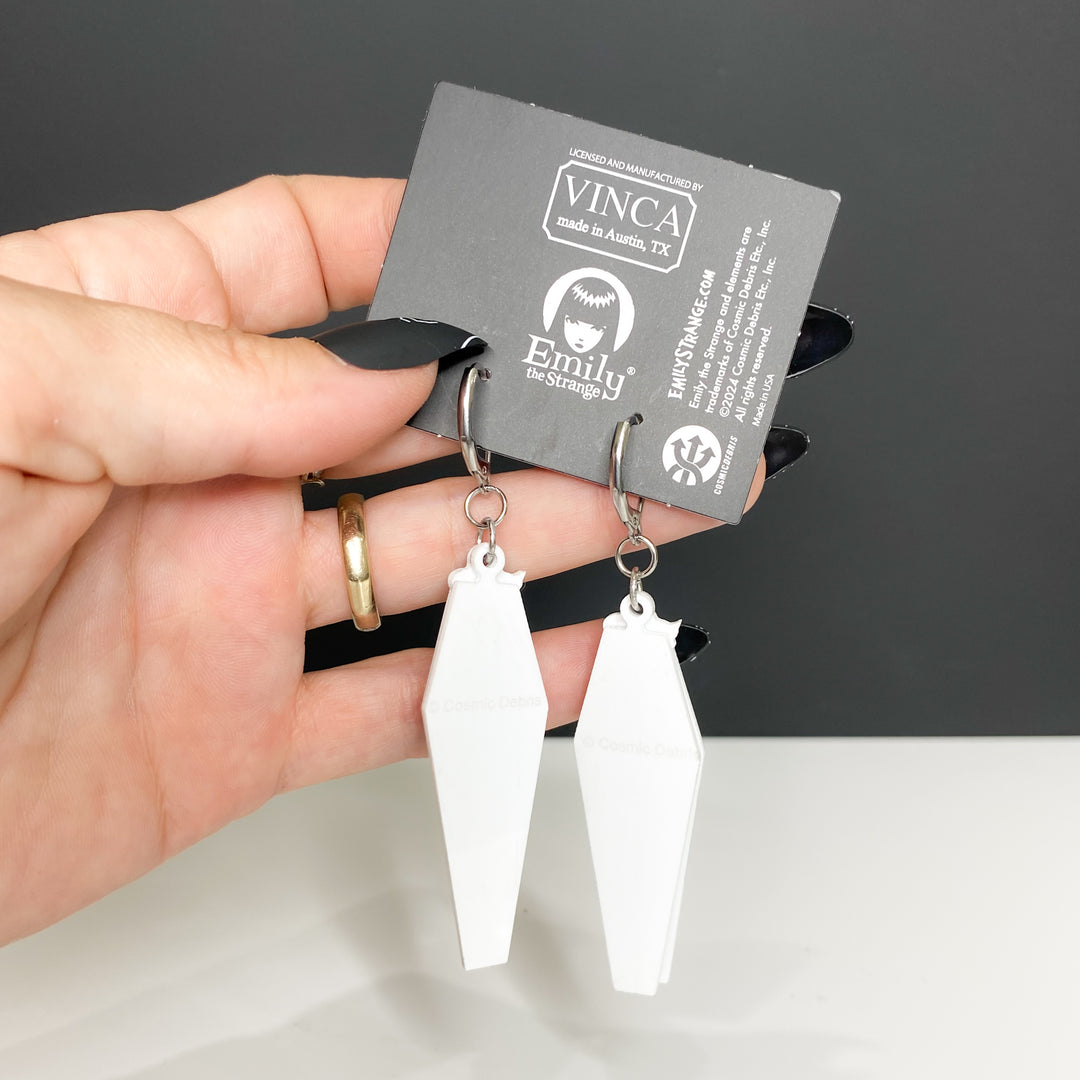 A hand holds the back plate of our officially licensed Emily the Strange "Don't Bother Meow" black stainless steel hook earrings set against a white and black background.