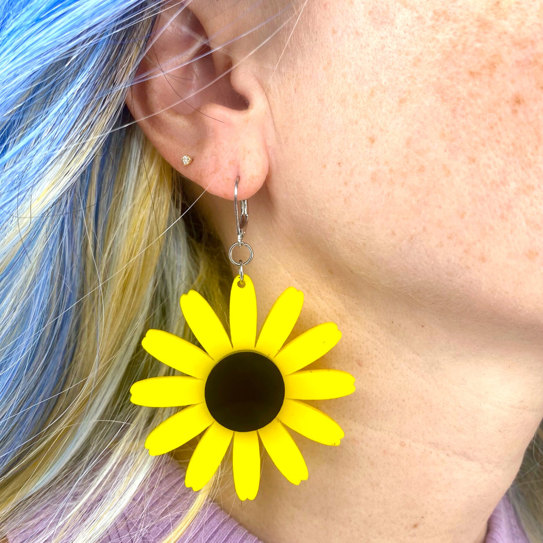 Wildflower Black-Eyed Susan Flower Dangle Earrings are worn by a woman with bright blue hair.