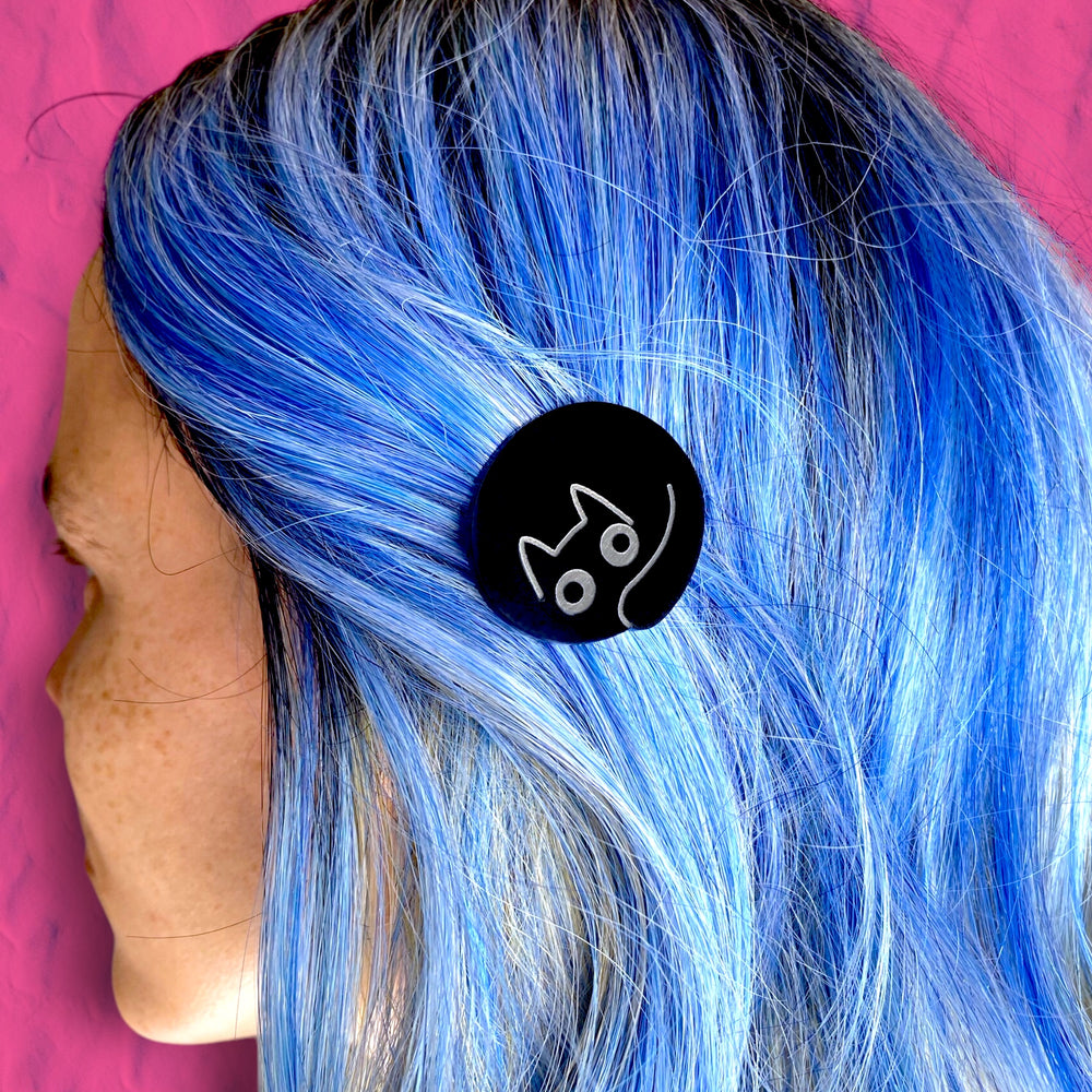 A woman with blue hair wears our Sarah's Scribbles Rounded Cat Hair Clip. 