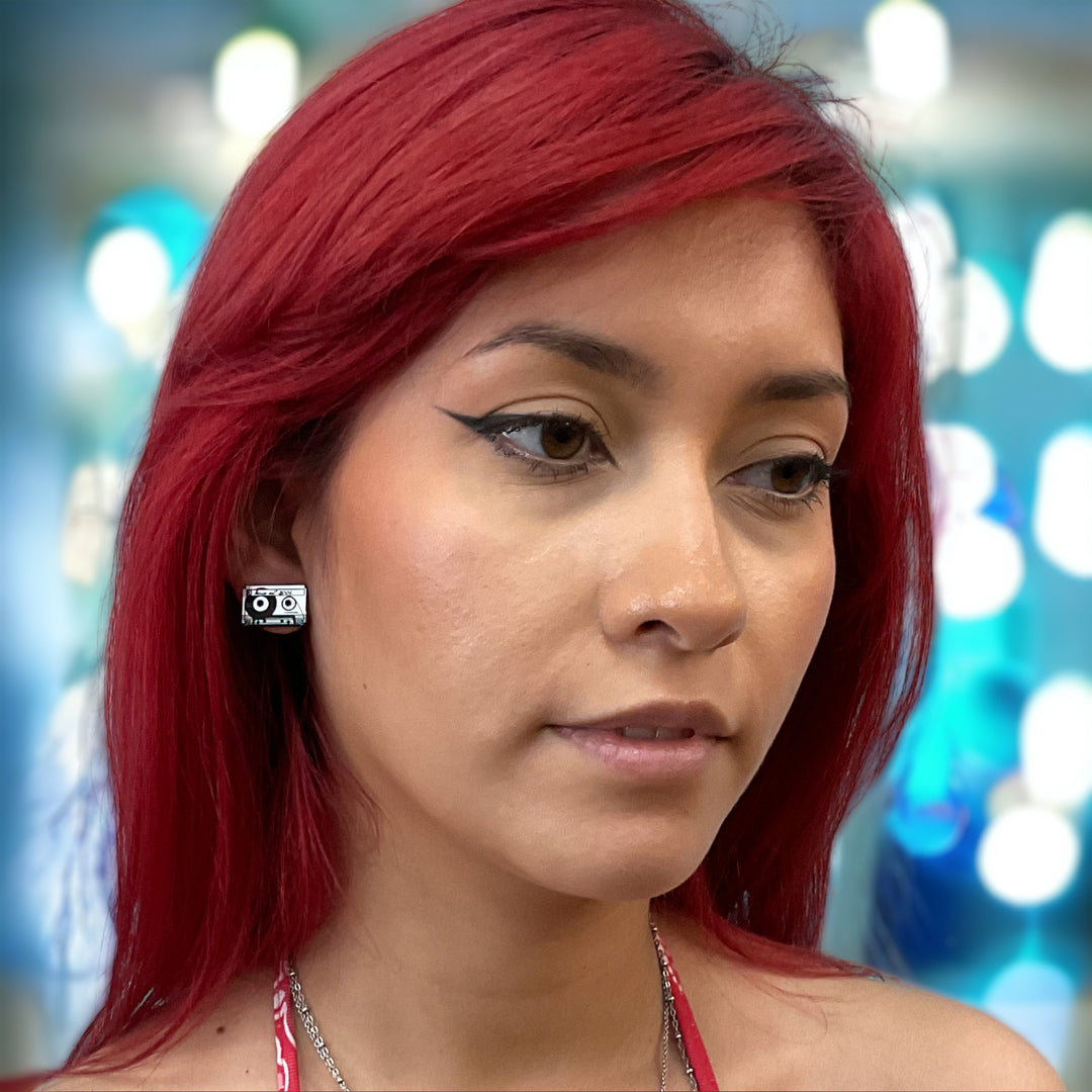 Silver tone, plastic cassette earrings on an alternatively styled model with bright red hair.