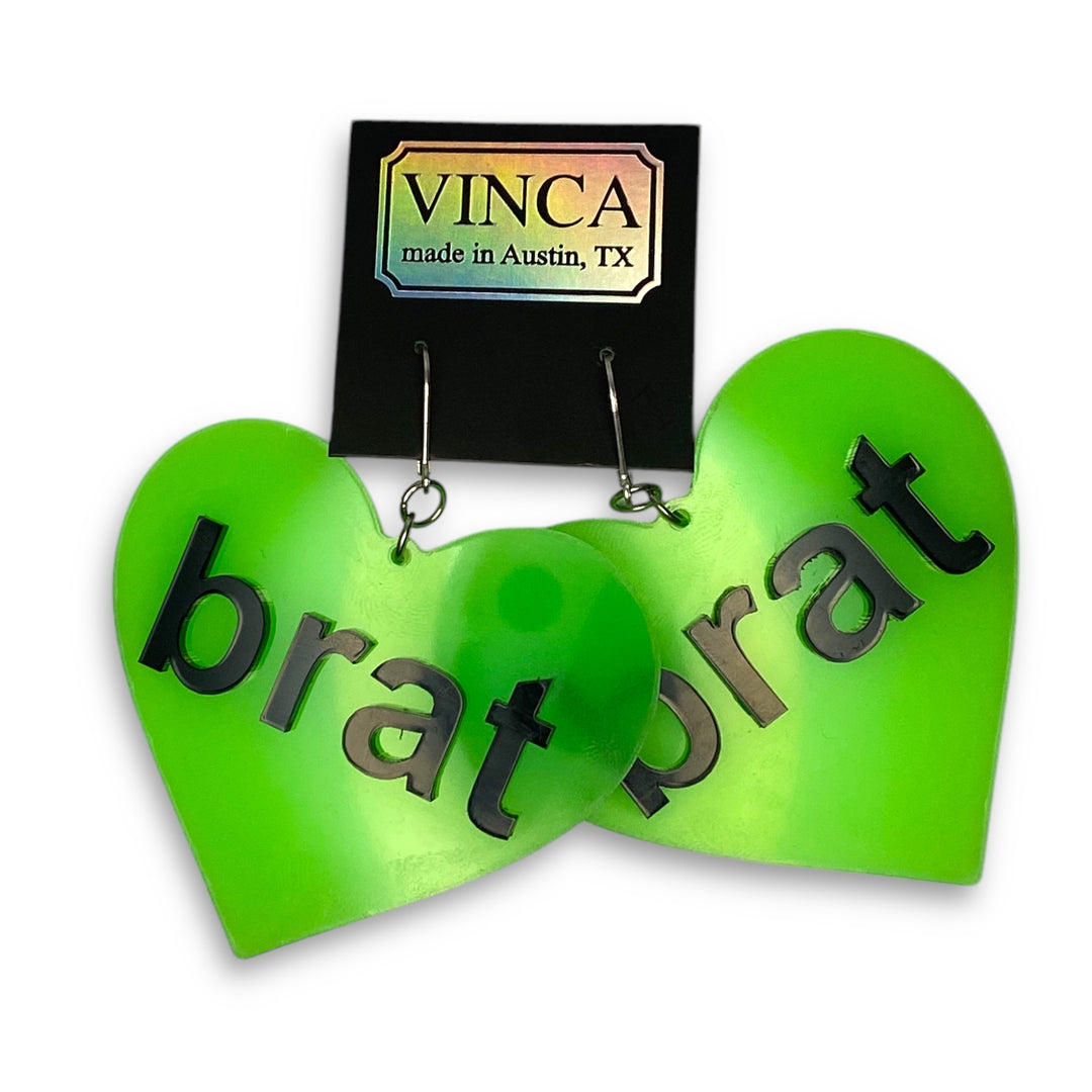 Brat Heart Dangle Earrings in glow green on a black Vinca branded card and set on a white background.