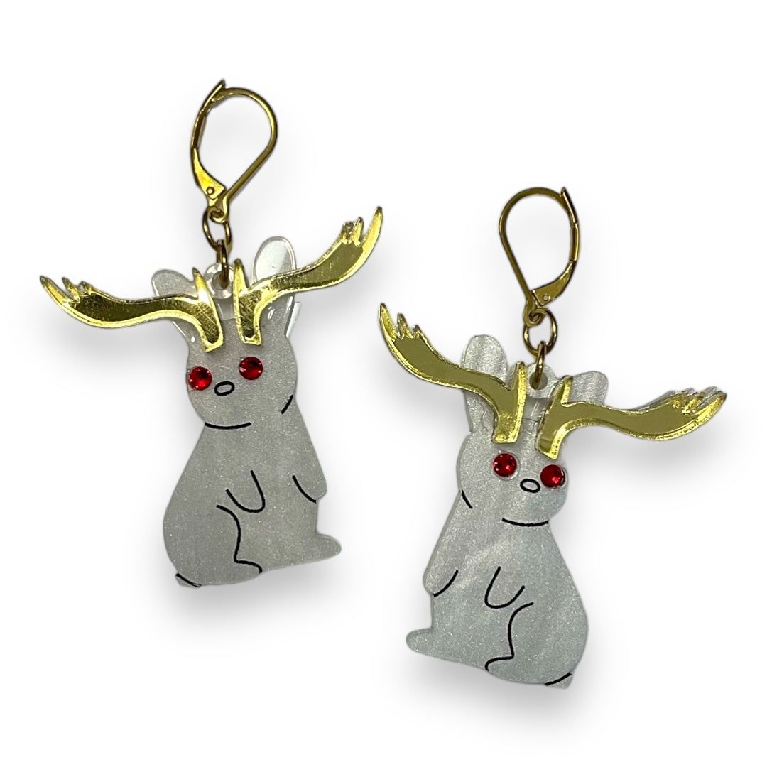 Handmade Sarah's Scribbles Cryptid Club Jackalope rabbit earrings in pearl white with red crystal eyes. We use gold plated stainless steel findings.