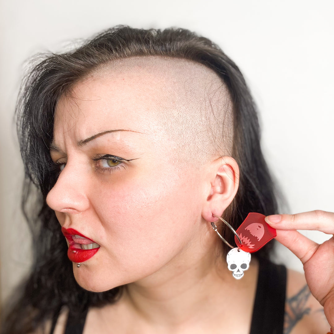 An edgy model wears our officially licensed Emily the Strange X-Ray Emily Skull Hoop Earrings against a white background. 