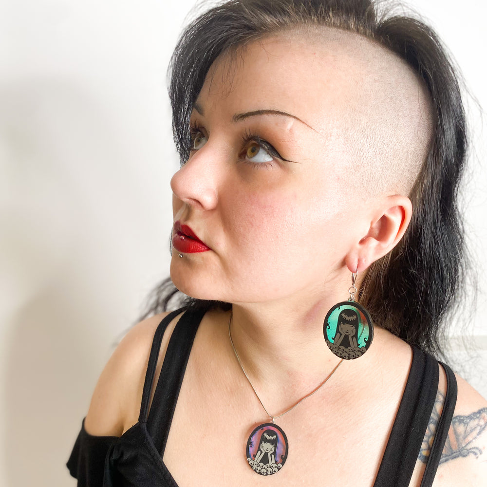 A model wears our Emily the Strange Misery Loves Company adjustable stainless steel snake chain necklace against a white background.