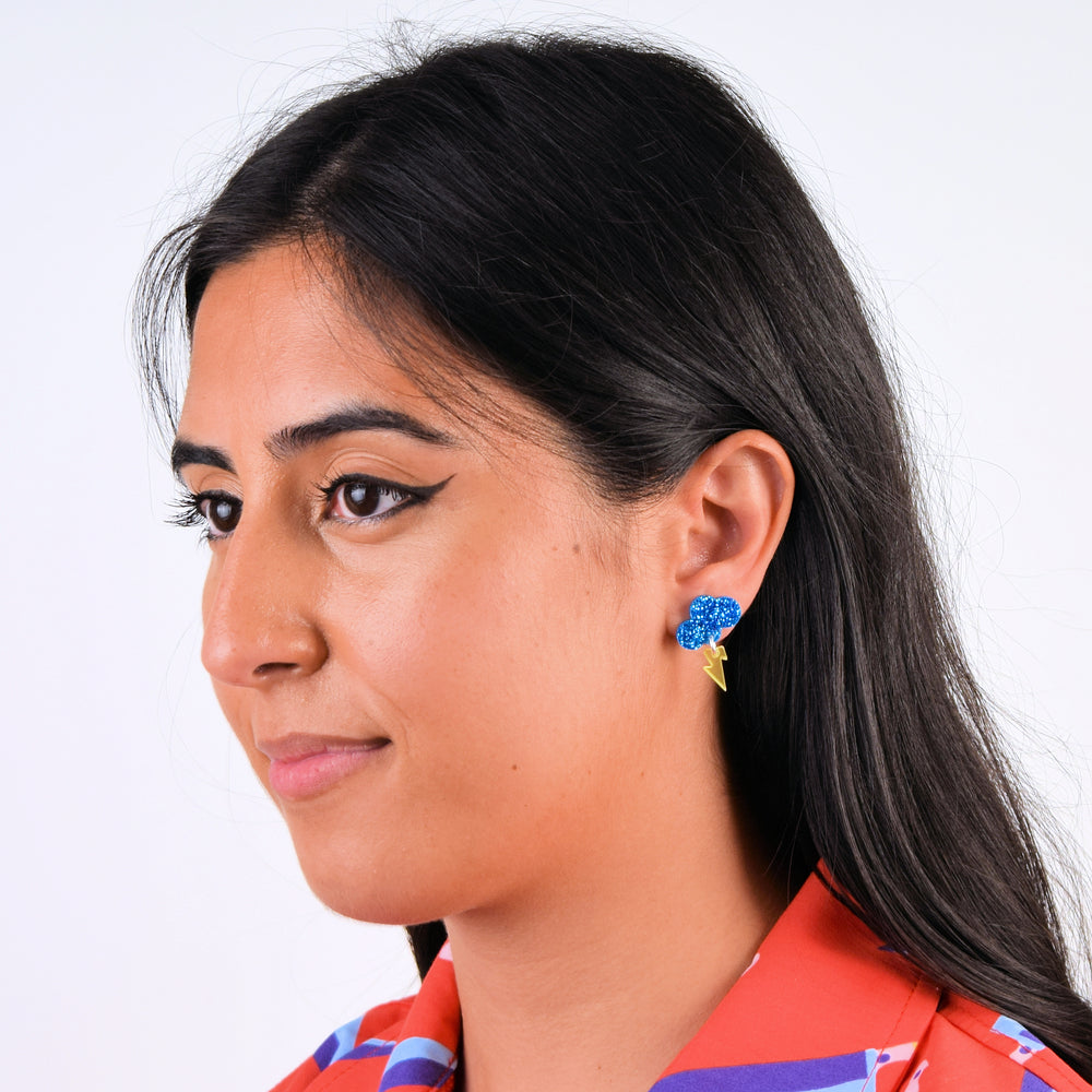 Model with dark hair wears an earring with a glitter blue cloud and a transparent frosted yellow lighting bolt.