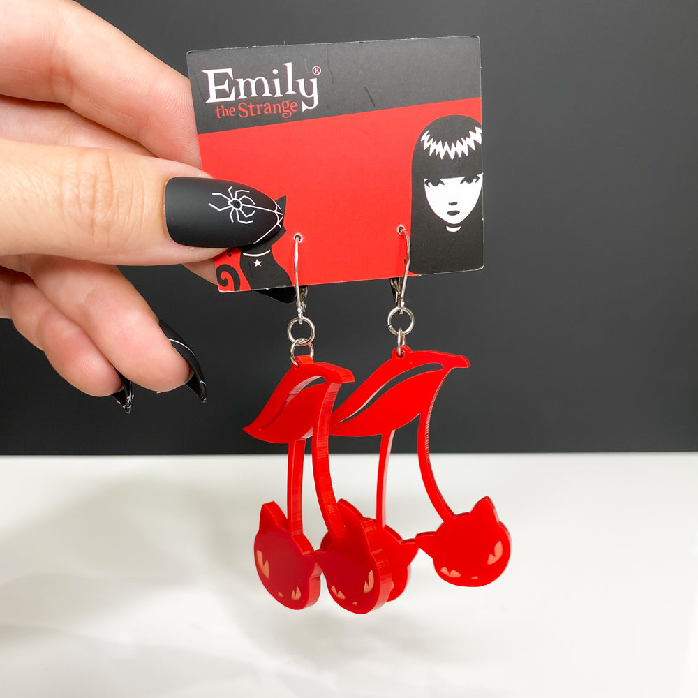 A model wearing black spider web nails holds our handmade officially licensed Emily the Strange red cat cherry hook dangle earrings against a white and black background. 