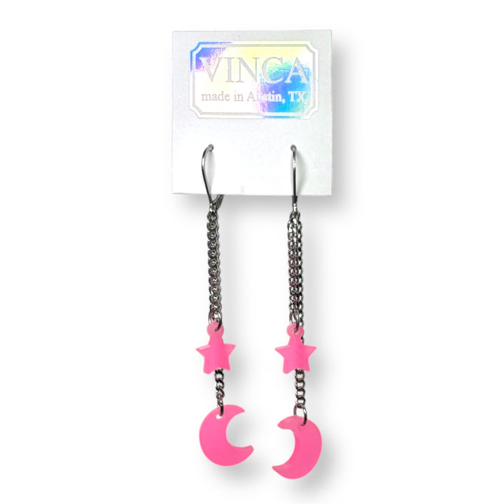 Handmade glow-in-the-dark star and moon dangle earrings with stainless steel findings on a white card. 