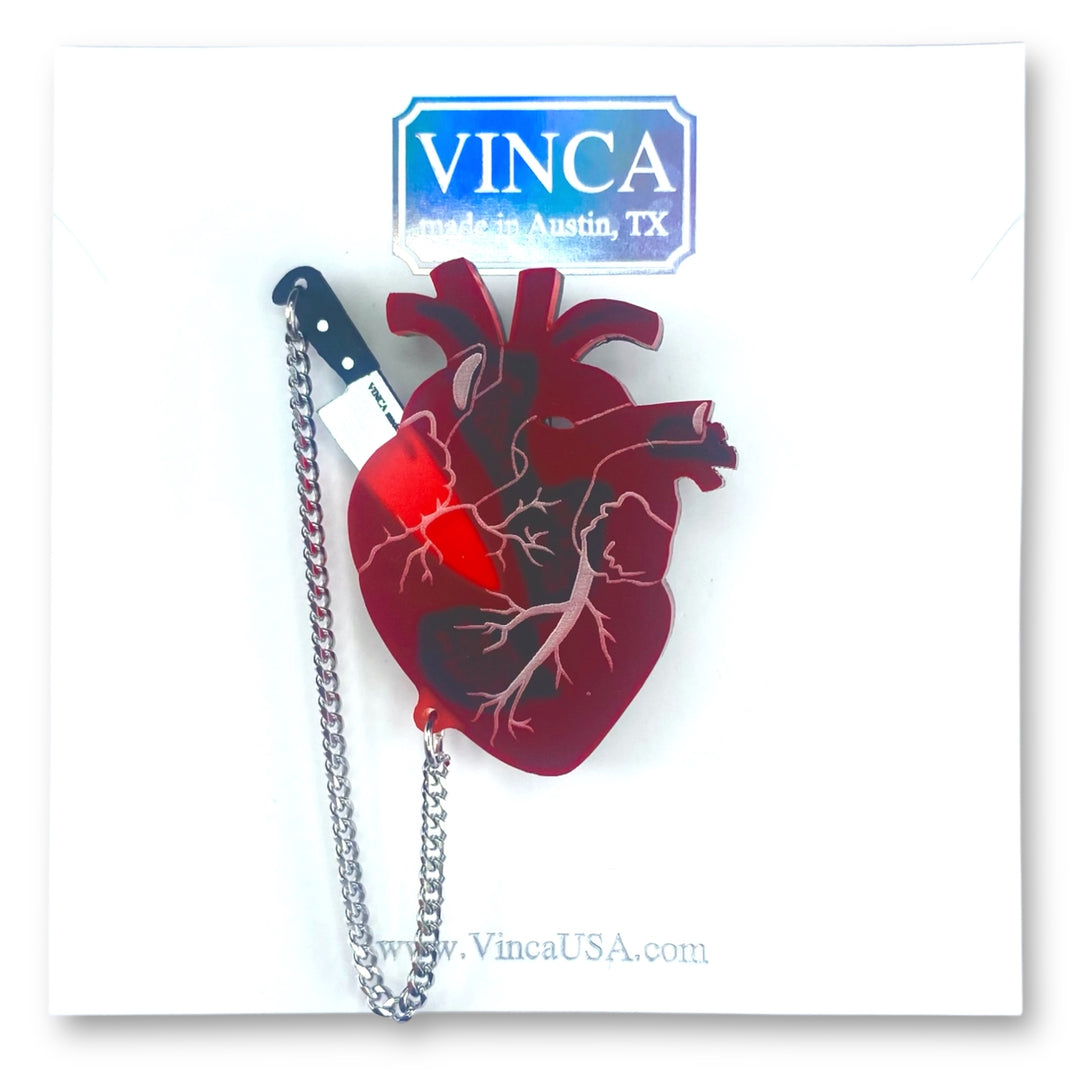 Interactive anatomical heart brooch pin with removable knife on a white branded Vinca card set against a white background.