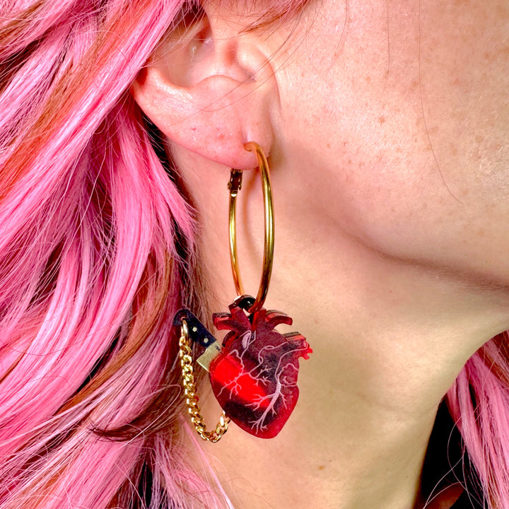 Goth horror frosted red anatomical heart hoops in gold plated stainless steel. Plastic brushed gold knife is removable. 