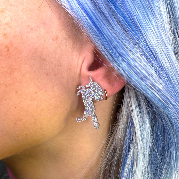 Handmade unicorn earring in glitter hologram on a woman with bright blue hair.