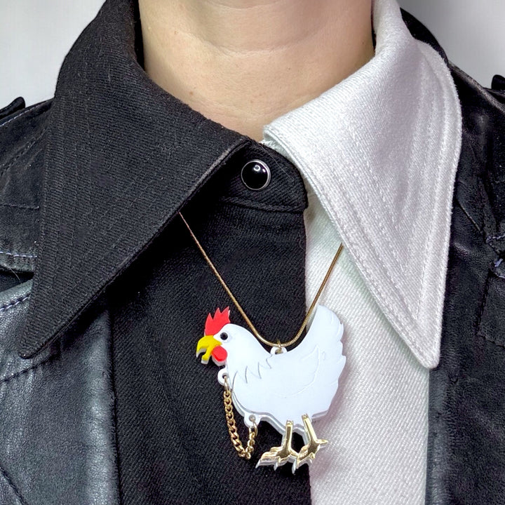 Headless chicken necklace with gold chain worn arounda collar that is half black and half white