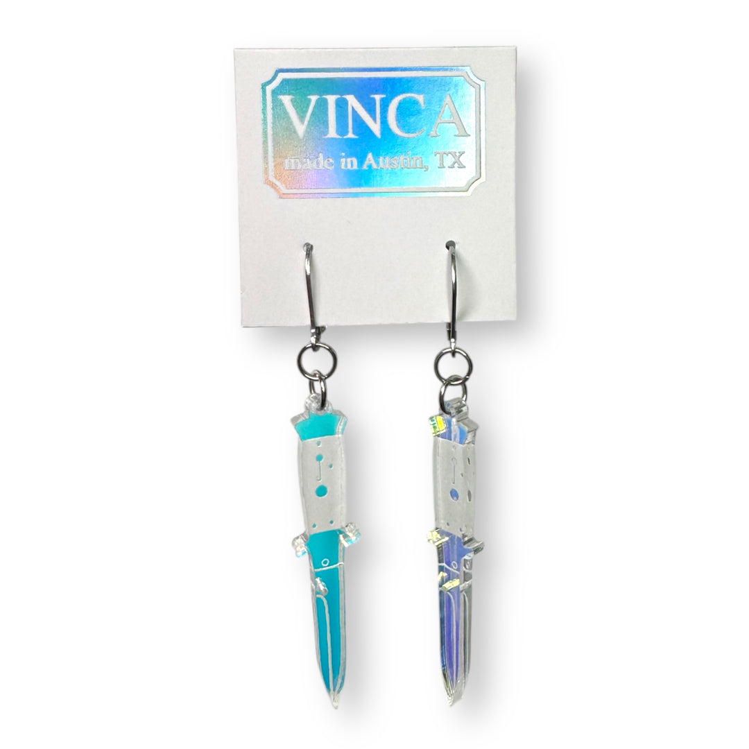 iridescent switchblade dangle earrings on a card against a white background