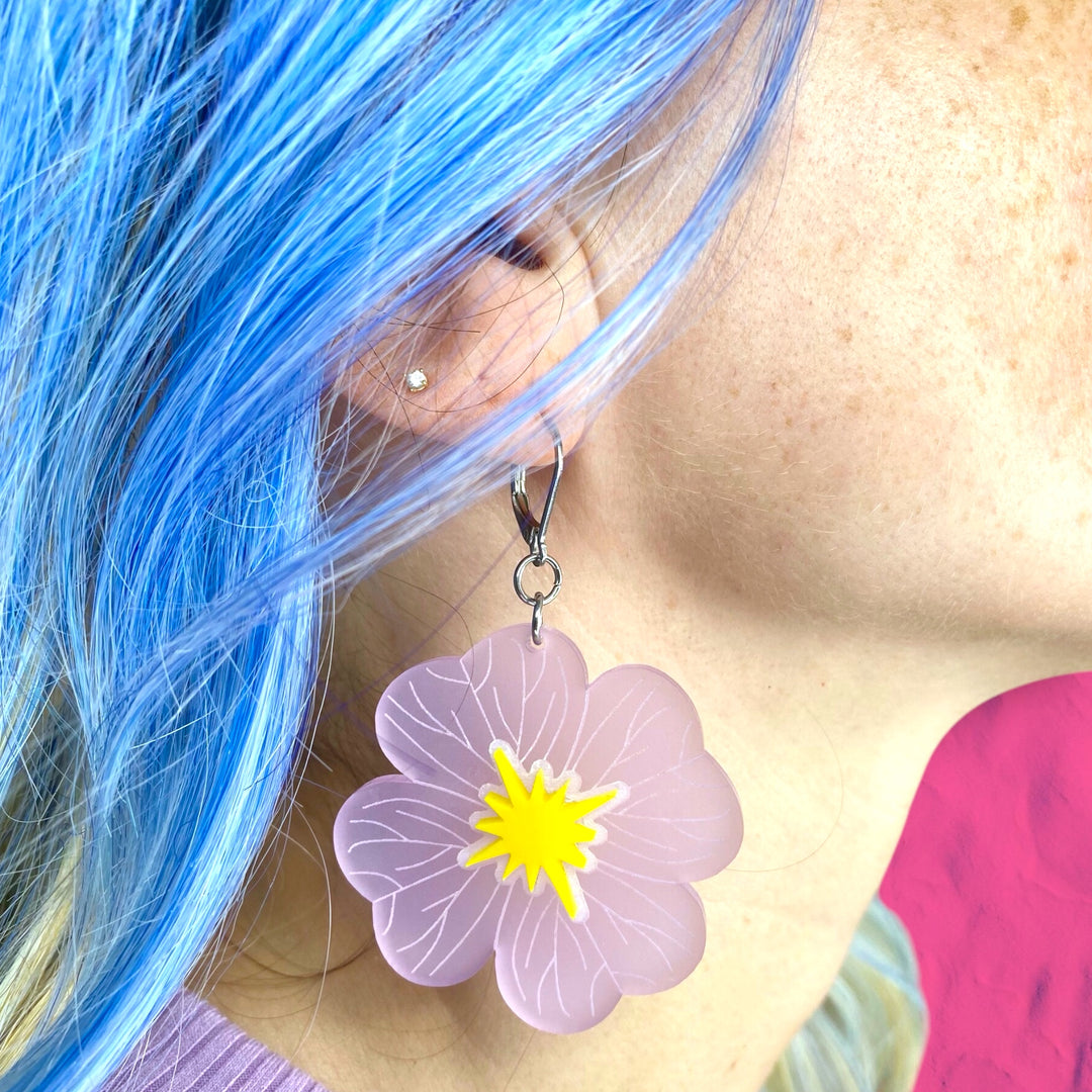 Wildflower Buttercup Flower Dangle Earrings are worn by a woman with bright blue hair.
