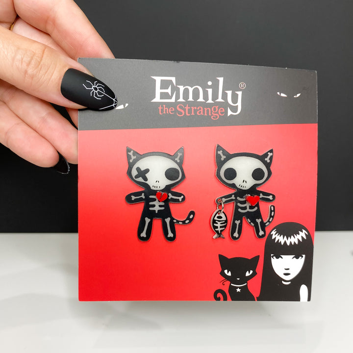 A model holds a packaged version of our officially licensed Emily the Strange goth cat skeleton earrings standing against a white and black background.