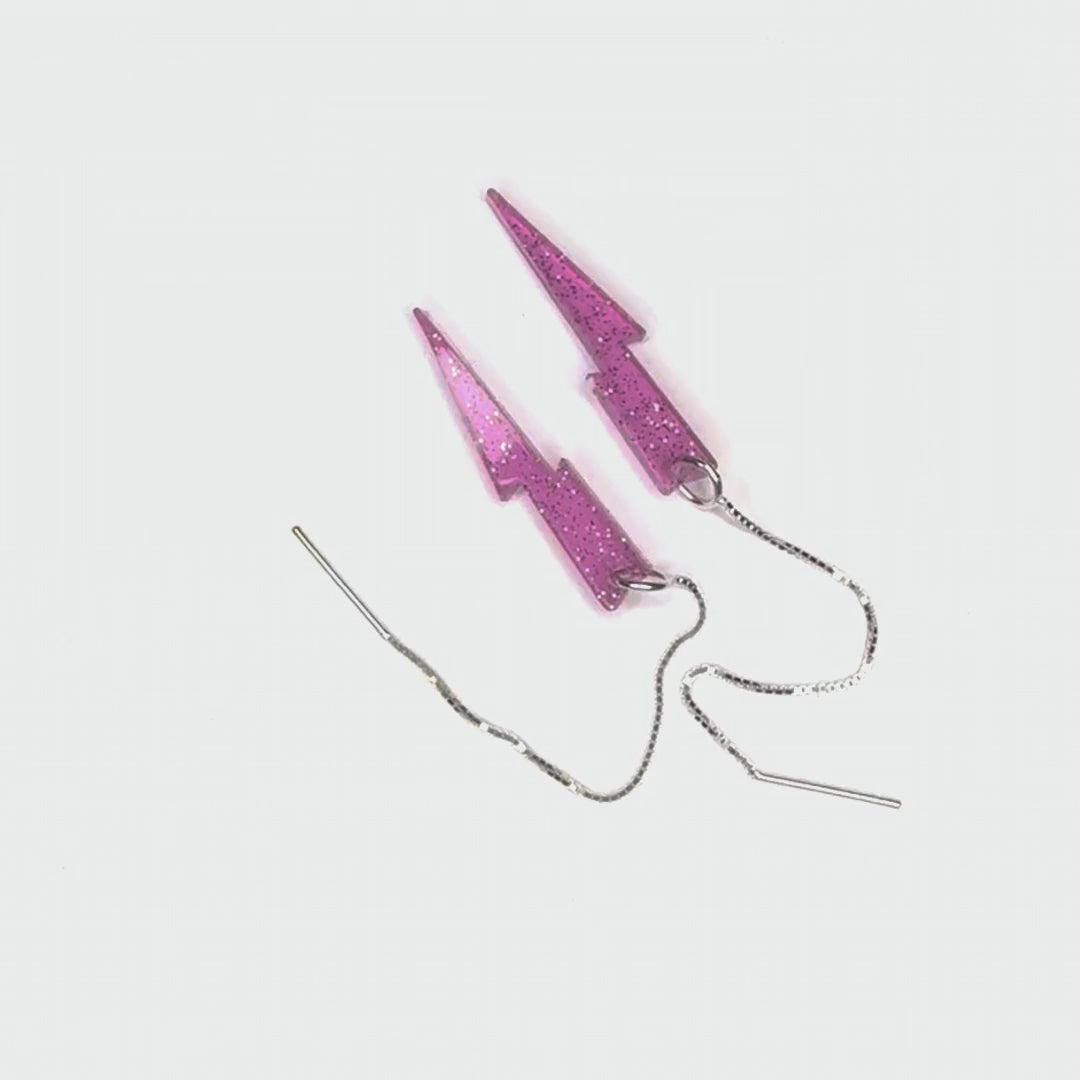 Video of clear pink glitter lightning bolt ear threaders turning to show the sparkle