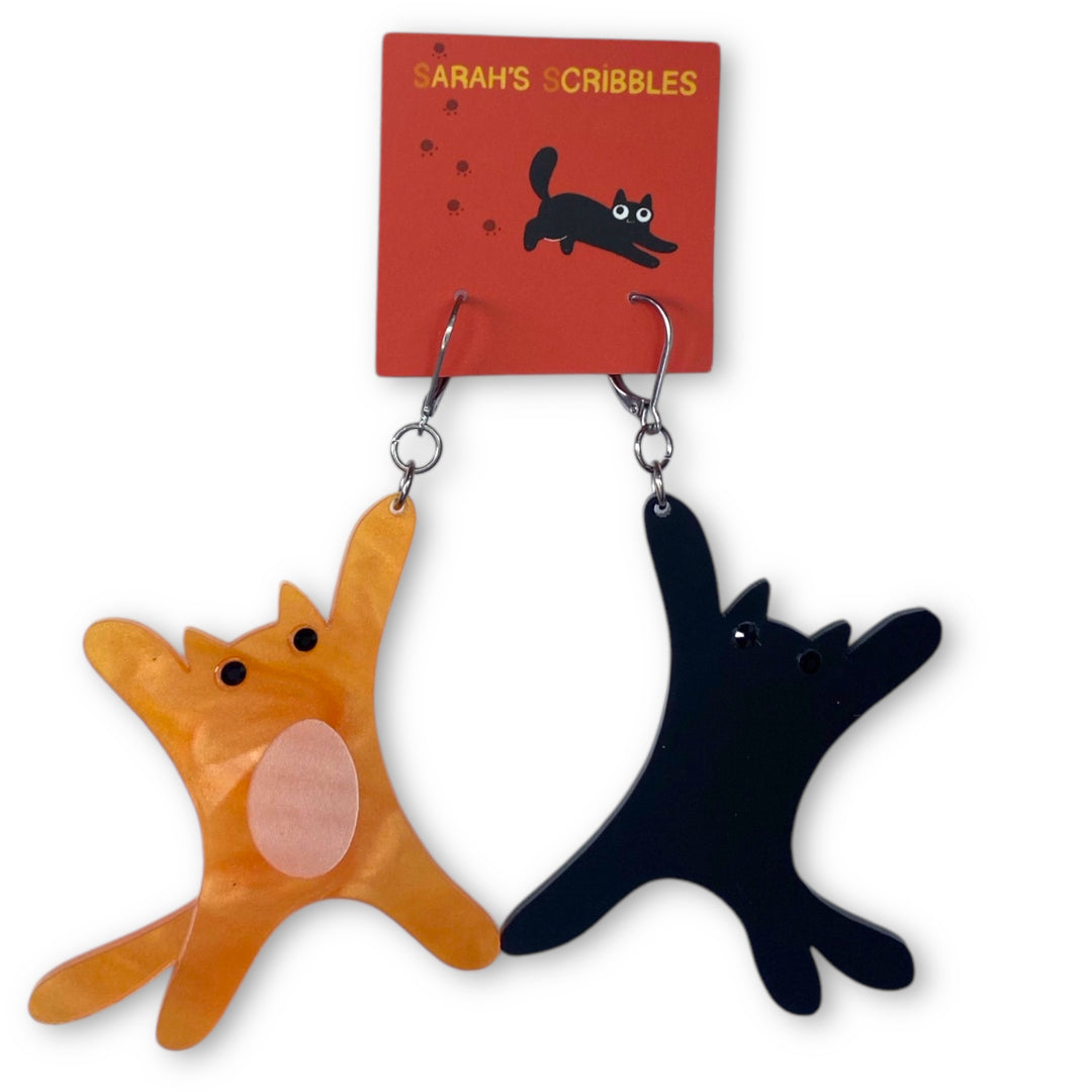 Our handmade Orange and Black Cat dangle earrings are on a Sarah's Scribbles branded card set against a white background.