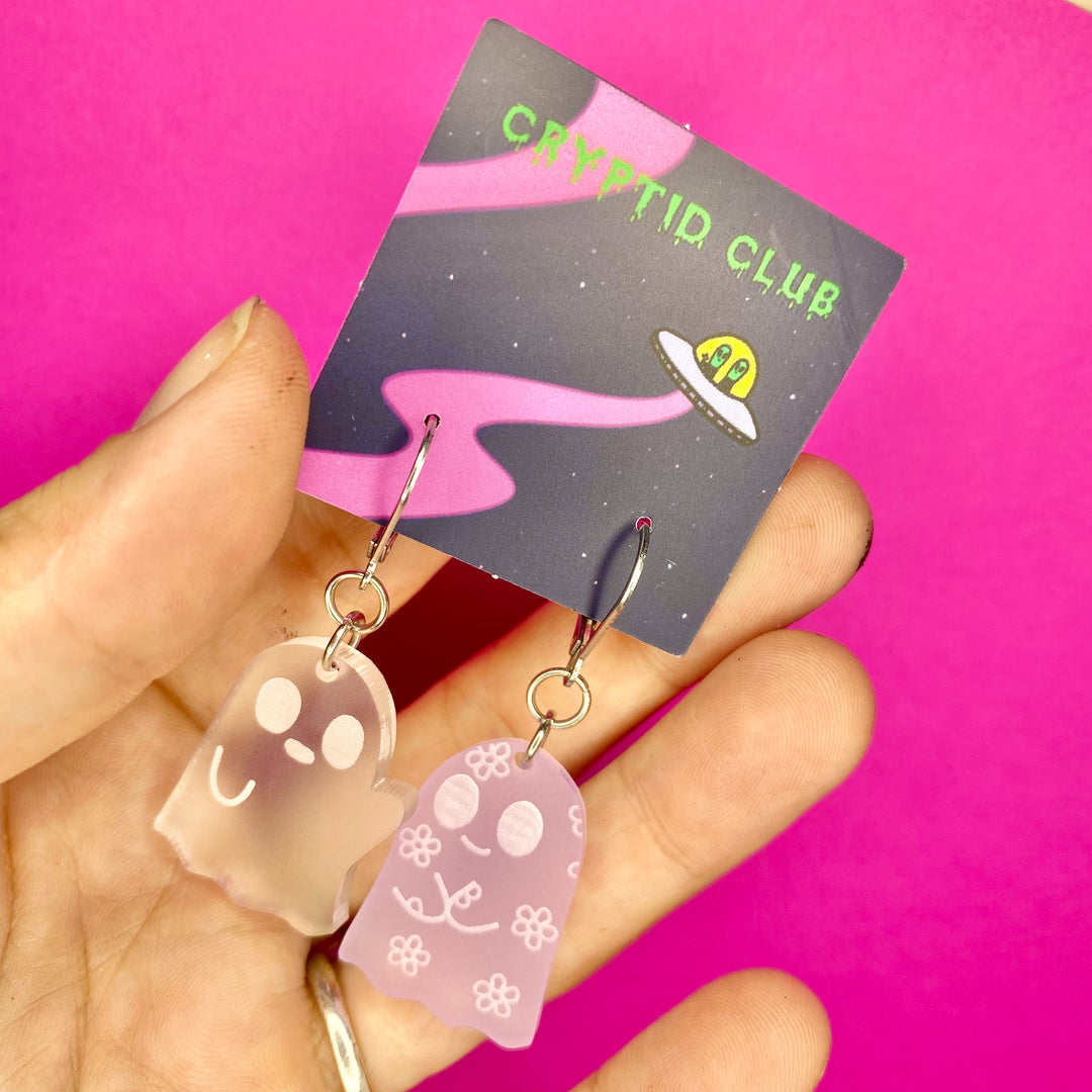 Sarah's Scribbles Cryptid Club dangle earrings are handmade and cut from frosted clear and lavender plastic. We use stainless steel findings for these pastel goth beauties!