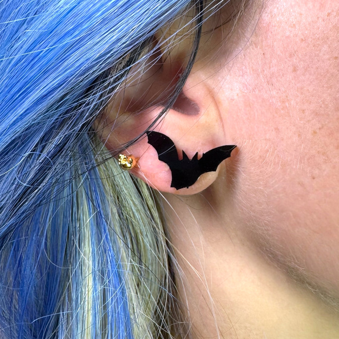 Handmade solid black bat earring stud earring on an ear with blue hair