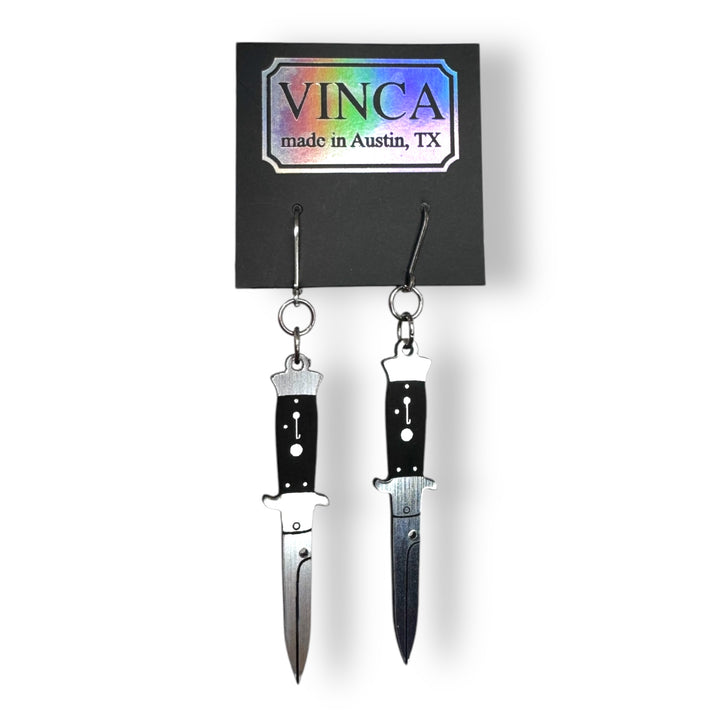 handmade switchblade dangle earrings on a black card against a white background