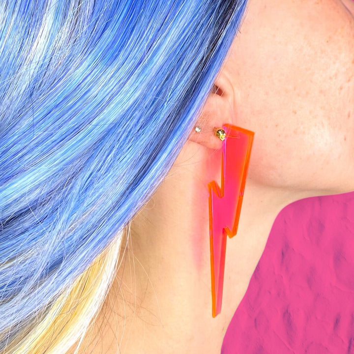 Transparent neon pink lighting bolt earring on a woman with bright blue hair. 