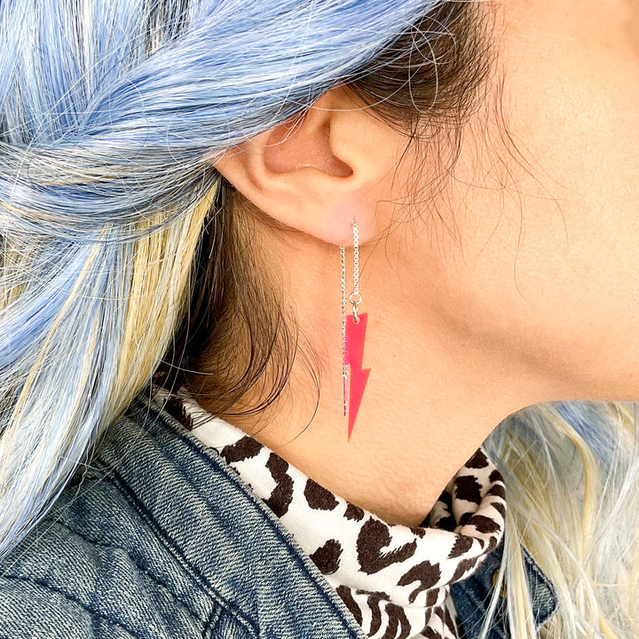 Transparent neon pink lightning bolt ear threader earrings glow under black light.