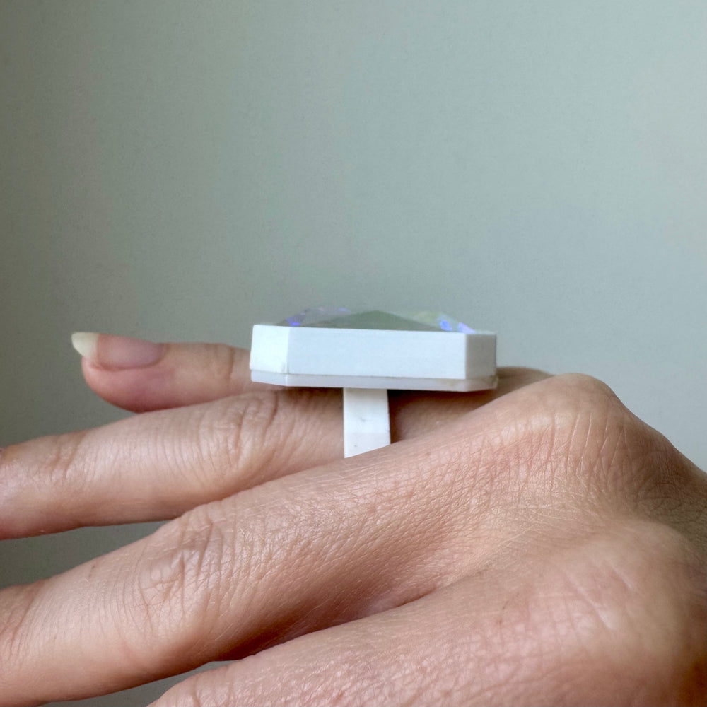 Sorceress Ring in white is shown worn on a finger from the side.