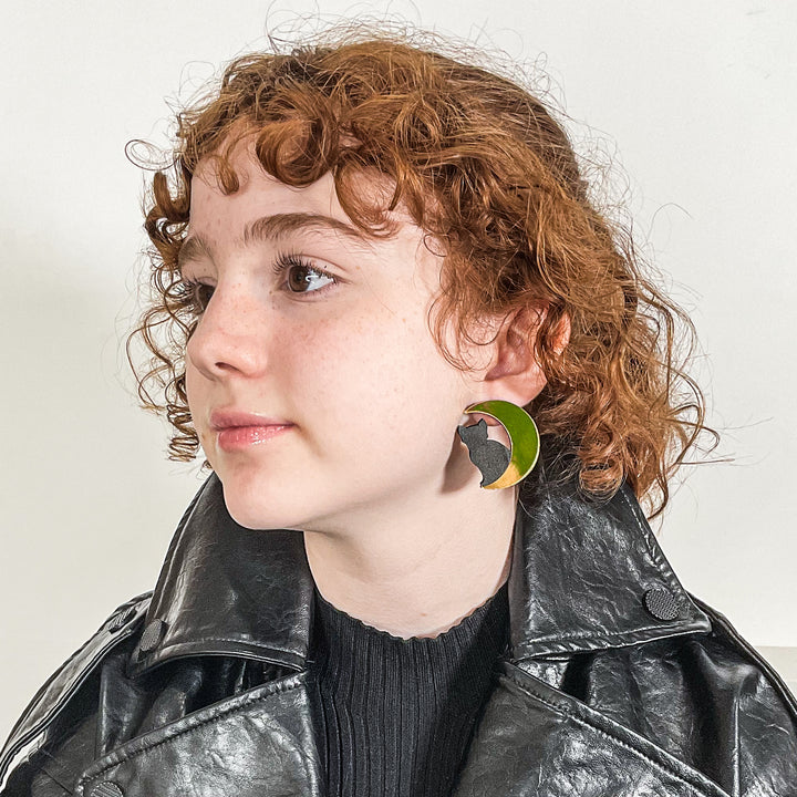 Cat in Moon earring on a young model with curly red hair and dressed in all black.