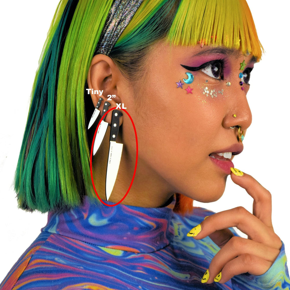 Decora girl with colorful hair, makeup and clothing, wears three sizes of knife earrings. The 3 inch knife earrings are circled in red.