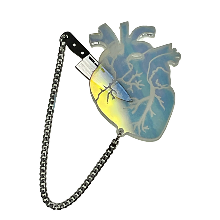 Our transparent iridescent anatomical heart brooch with removable plastic brushed silver tone knife is floating on a transparent background. 