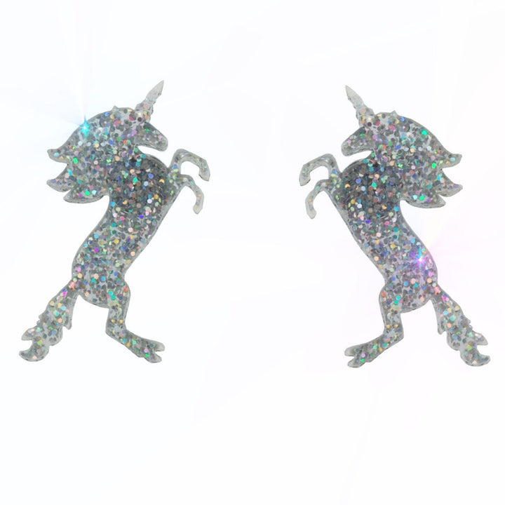 Glitter hologram unicorn earrings floating on a white background.